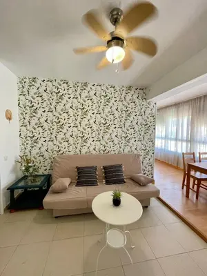 a living room with a couch and a ceiling fan at GATU Verano en la playa con parking, wifi, piscina in El Puerto de Santa María