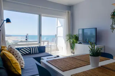 a living room with a blue couch and a large window at Apartamento Sea Views Rota in Rota