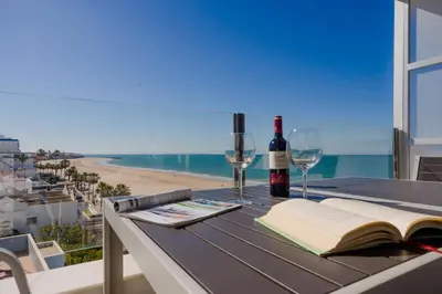 a table with a book and wine glasses on a balcony at Apartamento Sea Views Rota in Rota