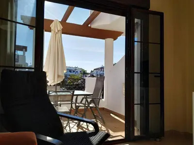 a room with a balcony with a chair and a umbrella at APARTAMENTO EN COTO DE SANCTI PETRI in Chiclana de la Frontera
