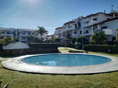 a swimming pool in a yard with buildings in the background at APARTAMENTO EN COTO DE SANCTI PETRI in Chiclana de la Frontera