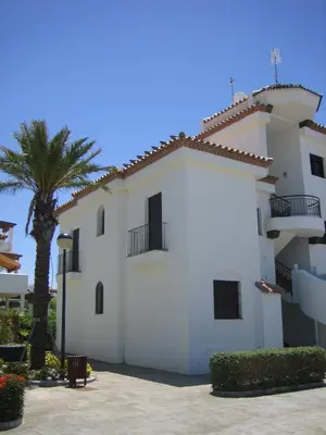 a white building with a palm tree in front of it at APARTAMENTO EN COTO DE SANCTI PETRI in Chiclana de la Frontera