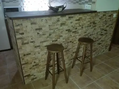 a counter with two stools in front of a brick wall at Casa 100m2 in Chiclana de la Frontera