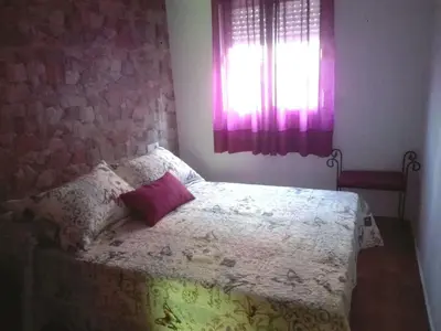 a bedroom with a bed with a pillow and a window at Casa 100m2 in Chiclana de la Frontera