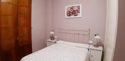 a white bedroom with a bed and two lamps at SAN JUSTO in Jerez de la Frontera