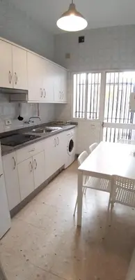a kitchen with white cabinets and a table and a table and chairs at SAN JUSTO in Jerez de la Frontera
