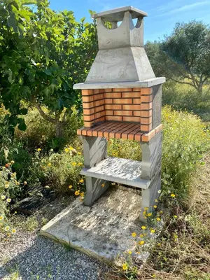 a small brick oven sitting in a field of flowers at The Farm Tiny House - Tiny Casa in Chiclana de la Frontera
