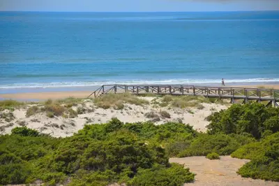 a bridge over the beach with a person walking on it at The Farm Tiny House - Tiny Casa in Chiclana de la Frontera