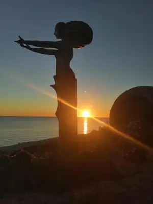 a statue of a woman standing on the beach at sunset at The Farm Tiny House - Tiny Casa in Chiclana de la Frontera
