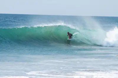 a man riding a wave on a surfboard in the ocean at The Farm Tiny House - Tiny Casa in Chiclana de la Frontera