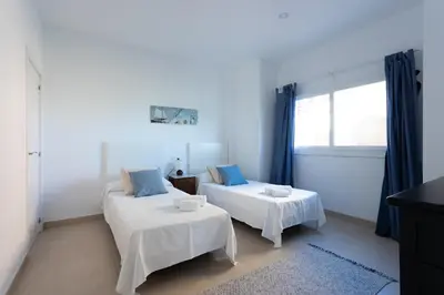 a white room with two beds and a window at Apartamentos Homing Puerto Sherry in El Puerto de Santa María