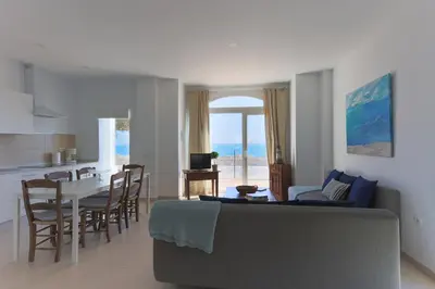 a living room with a couch and a table and a kitchen at Apartamentos Homing Puerto Sherry in El Puerto de Santa María