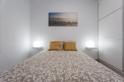 a bed in a white room with two lamps at SH Precioso Cruz. Acogedor y cerca del Mercado in Cádiz