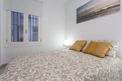 a white bedroom with a bed with a window at SH Precioso Cruz. Acogedor y cerca del Mercado in Cádiz