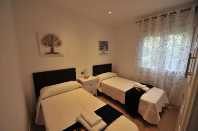 a small room with two beds and a window at Diseño Terraza dos baños Piscina in Jerez de la Frontera