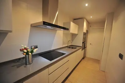 a kitchen with white cabinets and a vase of flowers at Diseño Terraza dos baños Piscina in Jerez de la Frontera