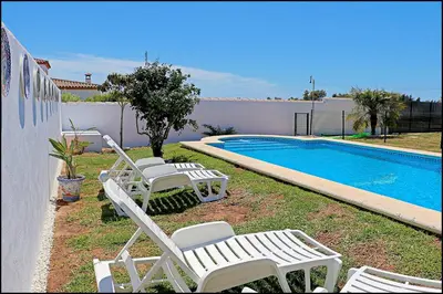 a group of lawn chairs next to a swimming pool at Bungalow Ramos III in Conil de la Frontera