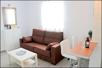 a living room with a brown couch and a table at Bungalow Ramos III in Conil de la Frontera