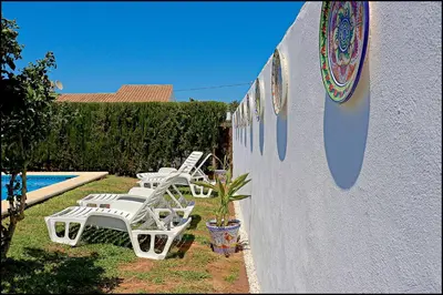 a group of white chairs sitting next to a wall at Bungalow Ramos III in Conil de la Frontera