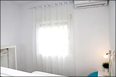 a bedroom with a window with white curtains at Bungalow Ramos III in Conil de la Frontera