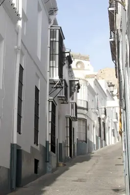 an alley with white buildings with black windows at Casa Atahona - Casita con Encanto in Medina Sidonia