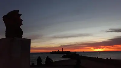 a group of people sitting on the beach at sunset at El Rincón del Tío de la Tiza in Cádiz