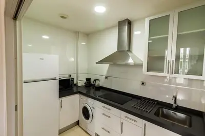 a kitchen with white cabinets and a sink and a stove at Casa Comillas - Apartamento Doble in Cádiz