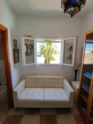 a living room with a white couch and a window at Villa Coral in Chiclana de la Frontera