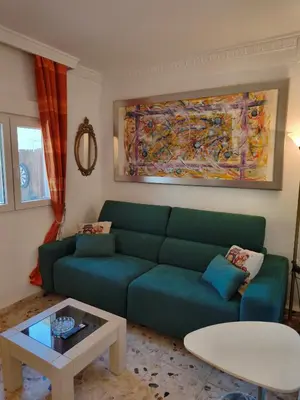 a living room with a green couch and a table at Villa Coral in Chiclana de la Frontera