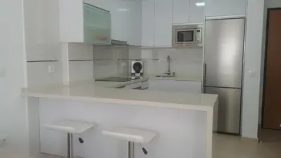 a white kitchen with a counter and a refrigerator at Apartamento Playa de Punta Candor in Rota