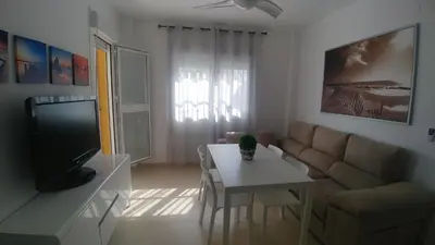 a living room with a couch and a table and a tv at Apartamento Playa de Punta Candor in Rota