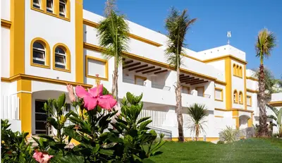 a large blue swimming pool with palm trees and buildings at Apartamento Playa de Punta Candor in Rota