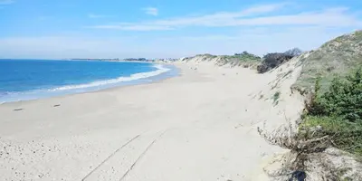 a sandy beach with people on it next to the ocean at Apartamento Playa de Punta Candor in Rota
