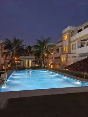 a large swimming pool at night in front of a building at Apartamento Playa de Punta Candor in Rota