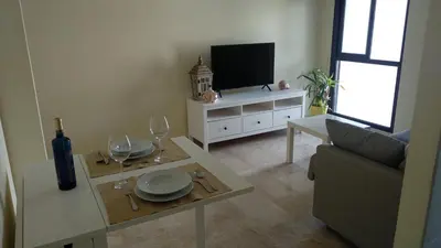 a living room with a tv and a table with wine glasses at ARBOLÍ DREAMS in Cádiz