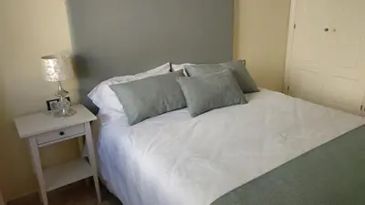 a white bed with pillows and a night stand with a lamp at ARBOLÍ DREAMS in Cádiz