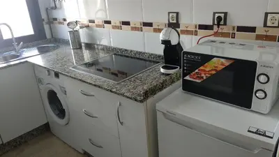 a kitchen with a counter with a microwave and a dishwasher at ARBOLÍ DREAMS in Cádiz