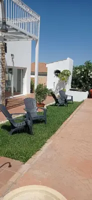 two benches sitting on the grass in front of a house at La Luciérnaga in Chiclana de la Frontera