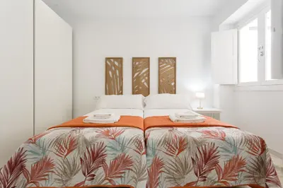a white bedroom with a large bed with a colorful blanket at Apartamento La Pepa de ORO by Cadiz4Rentals in Cádiz