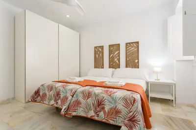 a white bedroom with a bed with an orange blanket at Apartamento La Pepa de ORO by Cadiz4Rentals in Cádiz