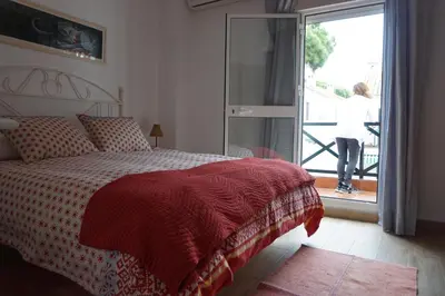 a woman standing on a balcony looking out a bedroom window at Adosado en playa de la Barrosa, casa Carlota in Chiclana de la Frontera