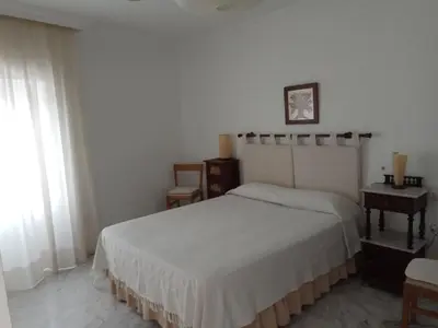 a bedroom with a white bed and a table at Casa GaLuz, entre la Sierra y el Mar in Alcalá de los Gazules