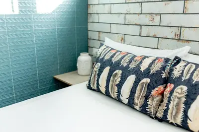 a white bed with a pillow and a brick wall at MODERNO LUJO in Novo Sancti Petri
