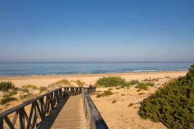 a wooden boardwalk leading to a beach with the ocean at Casa Venice in Chiclana de la Frontera