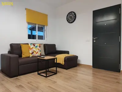 a living room with a couch and a table and a clock at Novoasis in Chiclana de la Frontera