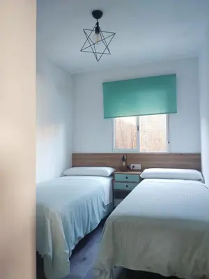 two beds in a room with a window at Novoasis in Chiclana de la Frontera
