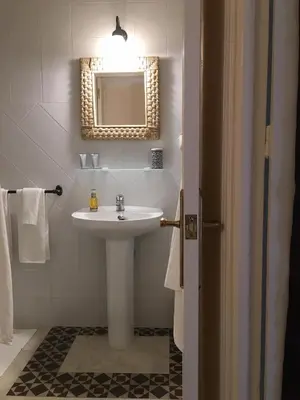 a white bathroom with a sink and a mirror at Número 9 in Medina Sidonia