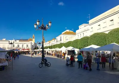 a group of people walking around a market with tents at Número 9 in Medina Sidonia