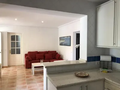 a kitchen with a red couch in a living room at Chalet La Costa in Chiclana de la Frontera