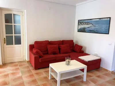 a living room with a red couch and a table at Chalet La Costa in Chiclana de la Frontera